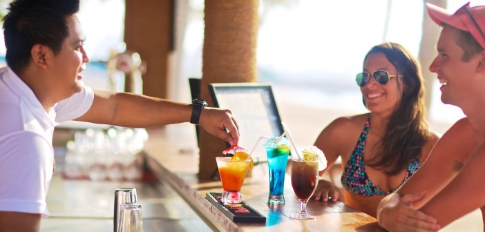 Kellner in der Coconut Grove Bar im Bin Majid Beach Resort bedient Paar am Strand